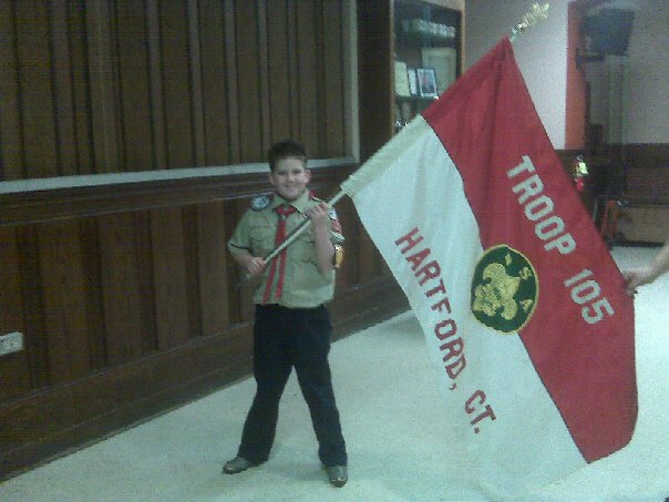A Boy Scout holding the Hartford Troop 105 flag